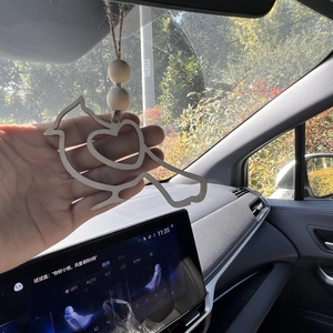 Detail of wooden bird pendant with heart cutout and beads hanging in car interior