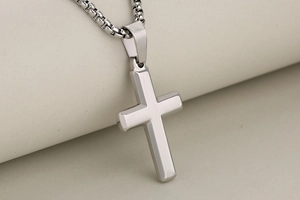 Close-up of polished stainless steel cross pendant with a classic box chain necklace