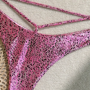 Detailed macro view of pink leopard print bikini bottoms with metallic finish fabric