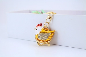 Detailed macro of a crystal-studded hen keychain with colorful enamel on a white box