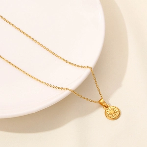 Primo piano della collana dorata con ciondolo a bussola solare su piatto bianco