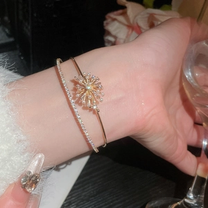 Close-up of double-layered gold bracelet featuring sunflower zircon and pearl charms