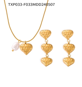 Détail de pendentifs en cœur et parure en perles avec texture dorée martelée vintage