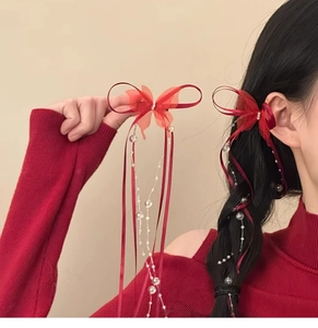 Detail of red bow hair clip with sparkling crystal butterfly and long ribbon tassels