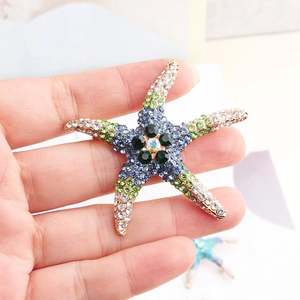 Detailed view of rhinestone starfish brooch in hand showing size and colorful crystals