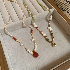 Detail of retro beaded necklaces with freshwater pearls and green gemstone pendants