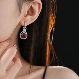 Dettaglio di eleganti orecchini in argento con gemma rossa indossati da una modella