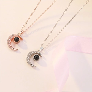 Detail of moon-shaped projection necklaces in rose gold and silver on pink silk background