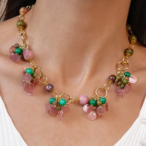 Macro shot of multi-material vintage necklace with green stone and pink shell charms