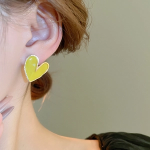 Gros plan sur les boucles d'oreilles cœur vert citron avec bords argentés et cristaux
