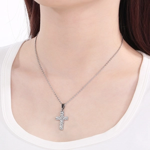 Close-up of a silver hammered cross necklace with crystal accents worn on a model's neck