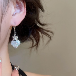 Close-up of a model wearing a heart-shaped zircon crown pendant earring in silver