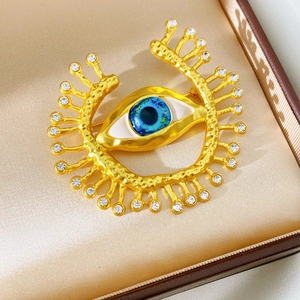 Macro detail of vintage gold evil eye brooch with blue resin and sparkling rhinestones