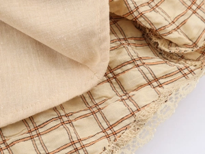 Gros plan sur tissu beige avec motif à carreaux orange et dentelle délicate