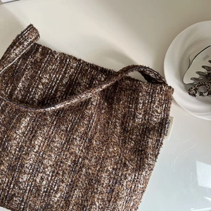 Close-up of brown tweed woven shoulder bag showing fabric texture and simple wish label
