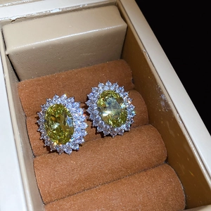 Macro shot of oval yellow zircon earrings with double cubic zirconia halo in jewelry box