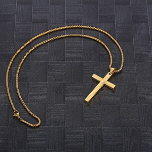 Macro shot of golden cross pendant with sunburst texture and matching box chain