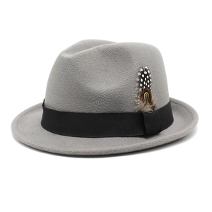Detail of dark grey wool fedora hat featuring black ribbon and spotted feather accent