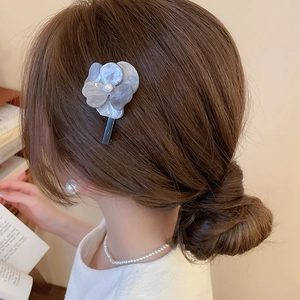 Barrette fleur en acétate blanc avec perle élégante portée sur cheveux lâchés