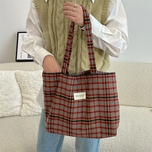 Detail showing high-quality plaid wool fabric and brand logo patch on the tote bag
