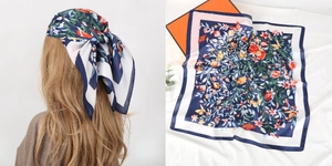 Detail of floral butterfly print silk scarf with navy blue borders and satin finish