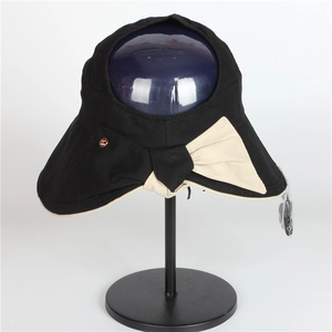 Detail of elegant black sun hat featuring a large cream bow and metal logo charm