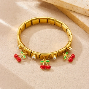 Gold plated stainless steel cherry charm bracelet with crystals on stone background