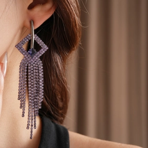 Elegant geometric earrings with cascading purple rhinestone tassels in a high-fashion style