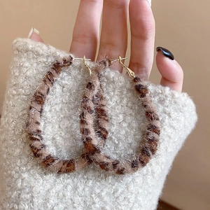 Close-up of plush leopard print hoop earrings with golden metal hooks for winter style