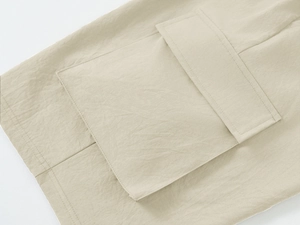 Detailed close-up of khaki cargo shorts showing large flap pocket and reinforced stitching