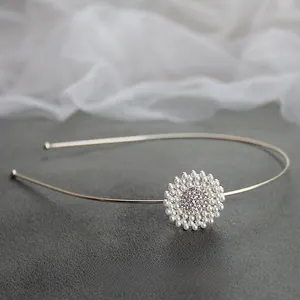 Dettaglio del cerchietto con fiori di perle dorate e strass su una fascia sottile