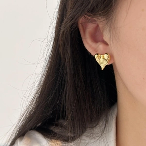 Close-up of golden irregular heart-shaped stud earring worn on model earlobe