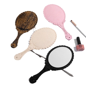Set of four vintage handheld mirrors with floral embossed handles in assorted colors