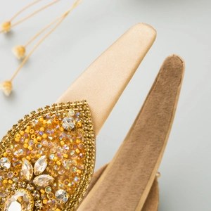 Vue détaillée du serre-tête doré champagne avec strass scintillants et perles de luxe