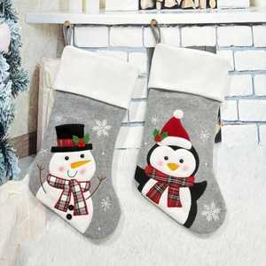 Christmas stockings featuring 3D snowman and penguin designs hanging on a white fireplace