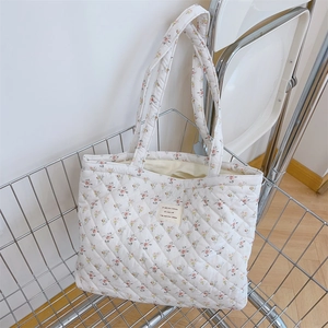 Détail du sac cabas fleuri matelassé avec étiquette jaune dans un panier métallique