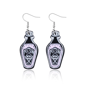 Macro detail of acrylic poison bottle earrings with skull motif and bat wing accents