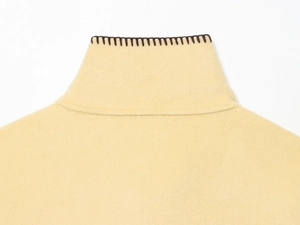 Detail of high-neck yellow wool coat with contrast dark brown stitching on the collar