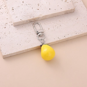 Cute yellow pear fruit keychain on stone slab with silver clip and green leaf detail