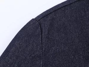 Detailed close-up of shoulder seam stitching on dark blue denim shirt for women