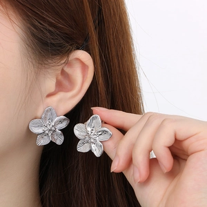 Detailed view of silver 3D flower stud earrings on model with high metallic luster