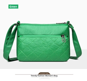 Detail view of green litchi texture leather crossbody bag with quilted pocket and zipper