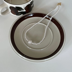 French vintage style pearl necklace with large center bead on elegant ceramic saucer