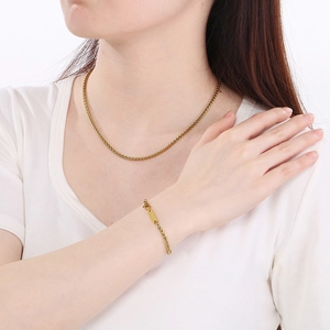 Primo piano dettagliato del set collana e bracciale a catena di grano dorata su modella