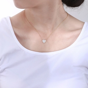 Detail view of heart pendant necklace with shimmering shell inlay and sparkling diamonds