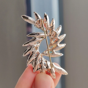 Back view of spiral crystal brooch in rose gold metal with colored gemstones and long pin