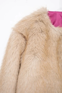Detail of faux fur coat in beige with vibrant pink lining and long fluffy texture