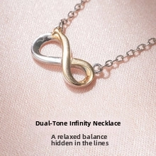 Macro detail of infinity symbol necklace with silver and gold two-tone finish on silk fabric