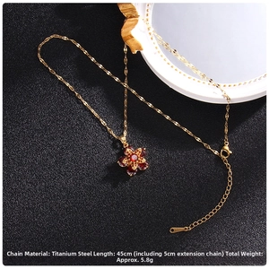 Detail view of gold titanium steel clover necklace with red zircon stone and 45cm chain