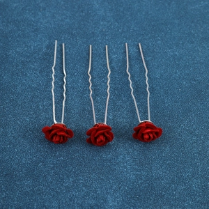 Close-up of three red flocked rose U-shaped hair pins with textured silver wavy metal stems